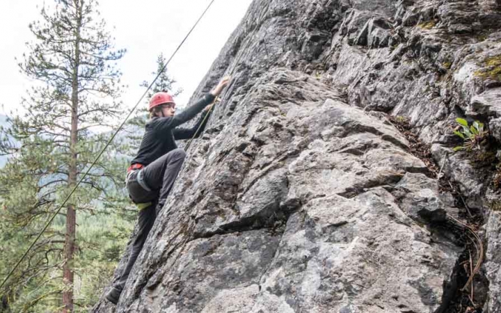 a student scales a rock wall on an outward bound trip for teens